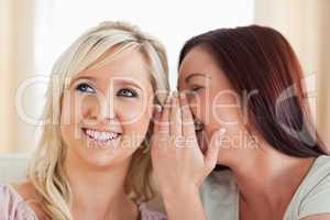 Gorgeous woman telling her friend a secret