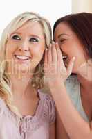 Smiling woman telling her friend a secret
