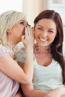 Smiling young woman telling her friend a secret