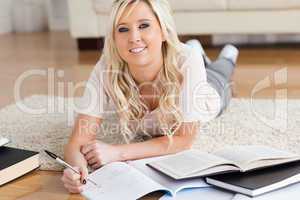 Blond charming College Student lying on the floor learning