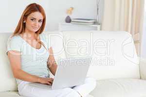 Cute woman sitting on a sofa with a notebook