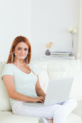 Charming woman sitting on a sofa with a notebook