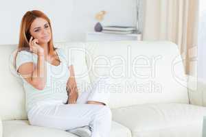 Smiling woman sitting on a sofa with a cellphone