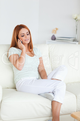 Young Woman sitting on a sofa with a phone