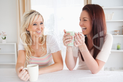 Cheerful Women sitting at a table with cups