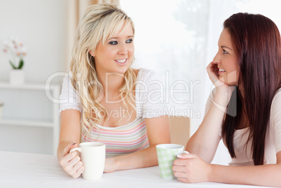 Joyful Women sitting at a table with cups
