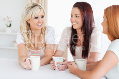 Smiling young Women sitting at a table with cups