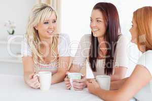 Smiling young Women sitting at a table with cups