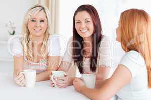 Charming young Women sitting at a table with cups