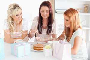 Gorgeous Women sitting at a table cutting a cake