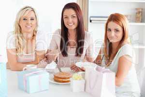 Smiling Women sitting at a table cutting a cake
