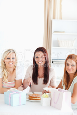 Charming Women sitting at a table cutting a cake