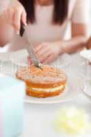 Charming Woman sitting at a table cutting a cake