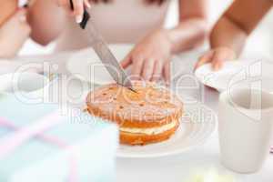 Cute Woman sitting at a table cutting a cake
