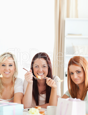 Smiling Women sitting at a table eating a cake