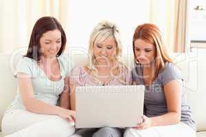 Cute women sitting on a sofa with a laptop