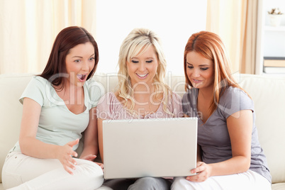 Amazed women sitting on a sofa with a laptop