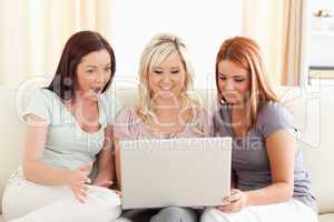 Amazed women sitting on a sofa with a laptop