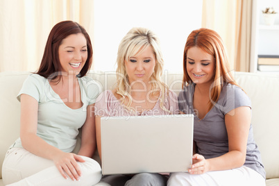 Laughing women sitting on a sofa with a laptop