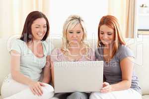 Laughing women sitting on a sofa with a laptop