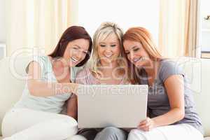 Cheering women lounging on a sofa with a laptop