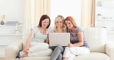 Gorgeous women lounging on a sofa with a laptop