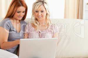 Charming Friends relaxing on a sofa with a laptop