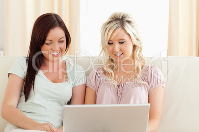 Smiling Friends relaxing on a sofa with a laptop