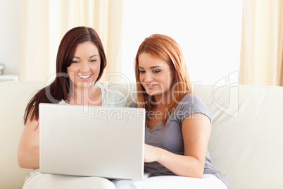 Excited Friends relaxing on a sofa with a laptop