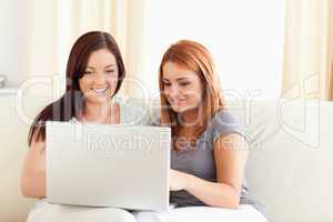 Excited Friends relaxing on a sofa with a laptop