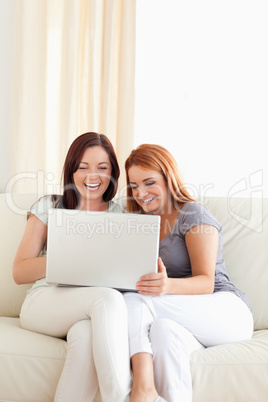 Gorgeous young women sitting on a sofa with a laptop