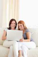 Gorgeous young women sitting on a sofa with a laptop