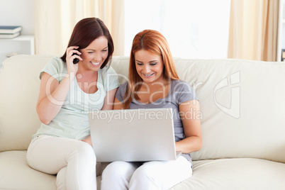 Women sitting on a sofa with a laptop and a phone