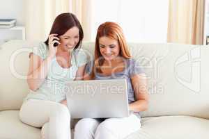 Women sitting on a sofa with a laptop and a phone