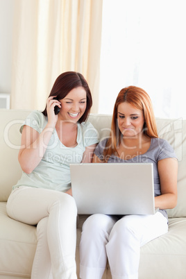 Young Women sitting on a sofa with a laptop and a phone