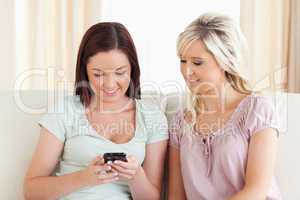 zwei Frauen sitzen mit Handy auf der Couch