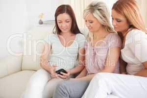 Freundinnen  sitzen mit Handy auf der Couch