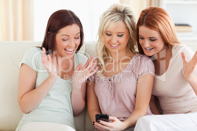 Freundinnen  sitzen mit Handy auf der Couch