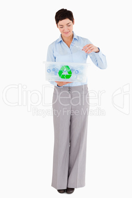 Woman putting an empty plastic bottle in a recycling box