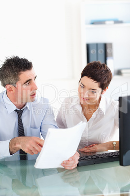 Portrait of coworkers talking about a document
