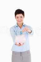Woman putting a bank note in a piggy bank
