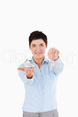 Businesswoman showing keys and a miniature house