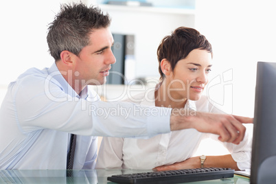 Man showing something to his coworker on a computer