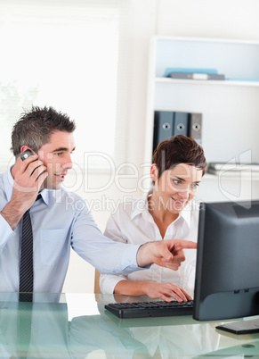 Portrait of a man showing something to his coworker on a compute