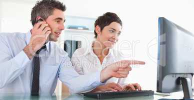Businessman showing something to his coworker on a computer