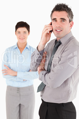 Portrait of a man making a phone call while his colleague is pos