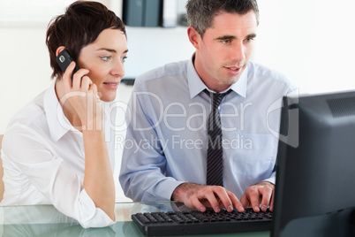 Woman telephoning while her colleague is using a computer