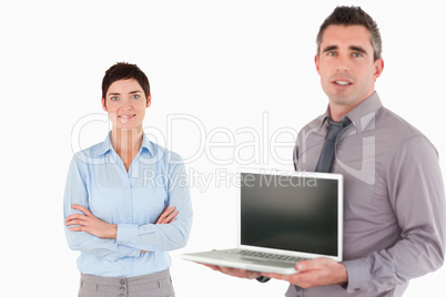 Office worker showing a notebook while his colleague is posing