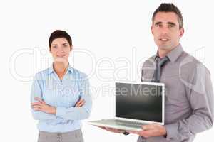 Office worker showing a notebook while his colleague is posing