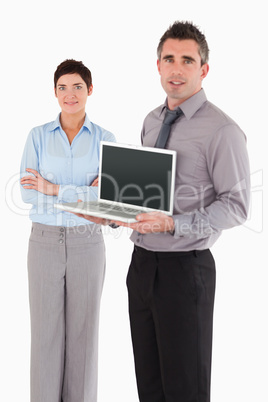 Portrait of a man showing a notebook while his colleague is posi